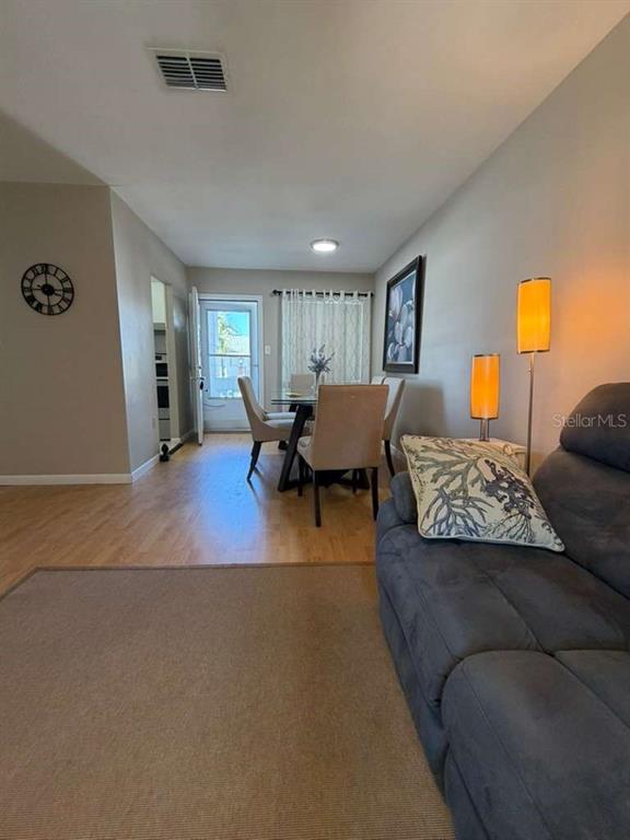 A living room with a gray sofa leads into a dining area with a glass table — 1832 SUNNY DRIVE UNIT D-32, BRADENTON, FL