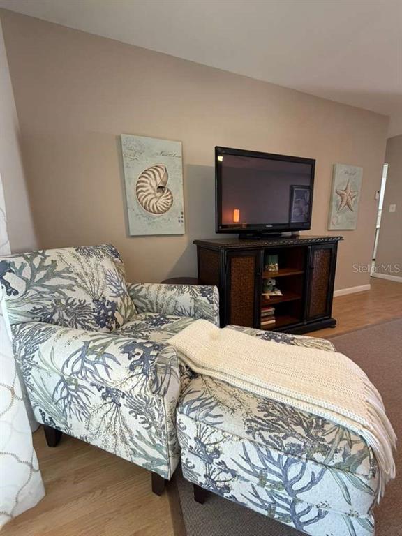 A patterned armchair with an ottoman sits in a living room near a television console — 1832 SUNNY DRIVE UNIT D-32, BRADENTON, FL