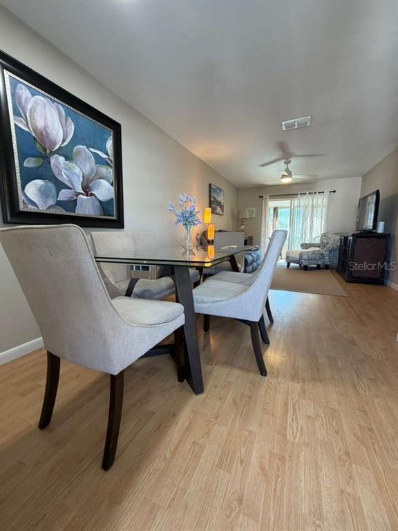 A dining area features a glass table, upholstered chairs, and a large floral wall art piece — 1832 SUNNY DRIVE UNIT D-32, BRADENTON, FL