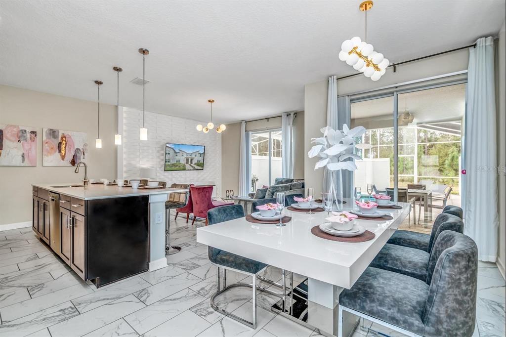A modern kitchen and dining area with white marble floors, a large island, and patio access — 640 PEBBLE BEACH DRIVE, DAVENPORT, FL