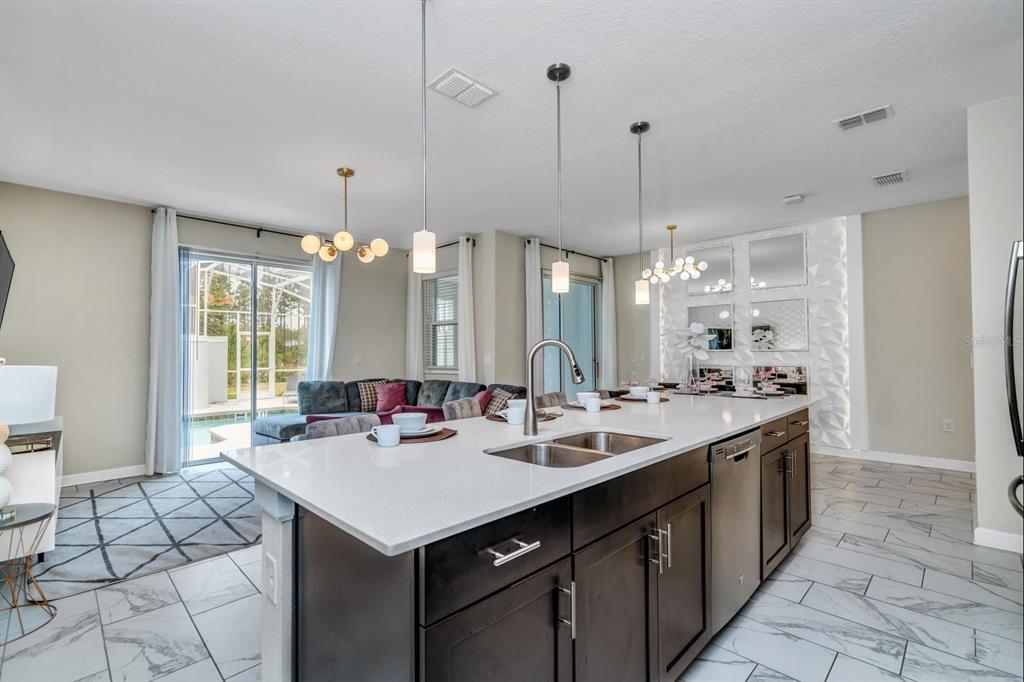 A kitchen island with a double sink sits before a living area with sliding doors — 640 PEBBLE BEACH DRIVE, DAVENPORT, FL