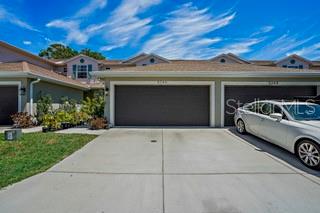 A white car is parked in the driveway of a tan townhouse with a garage — 5246 NEIL DRIVE, ST PETERSBURG, FL