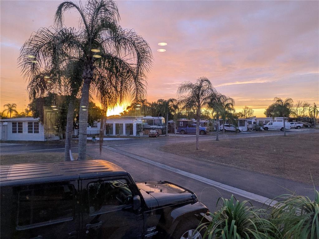 A black Jeep is parked in the foreground of a residential street at sunset — 46900 BERMONT ROAD UNIT 1L, PUNTA GORDA, FL