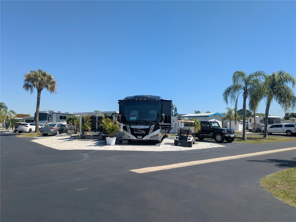 A large motorhome is parked on a paved lot with a golf cart and car — 46900 BERMONT ROAD UNIT 1L, PUNTA GORDA, FL