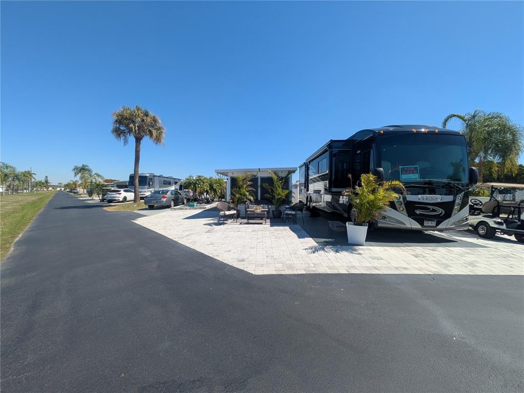 A paved lot features a large black motorhome, a small outdoor structure, and patio furniture — 46900 BERMONT ROAD UNIT 1L, PUNTA GORDA, FL
