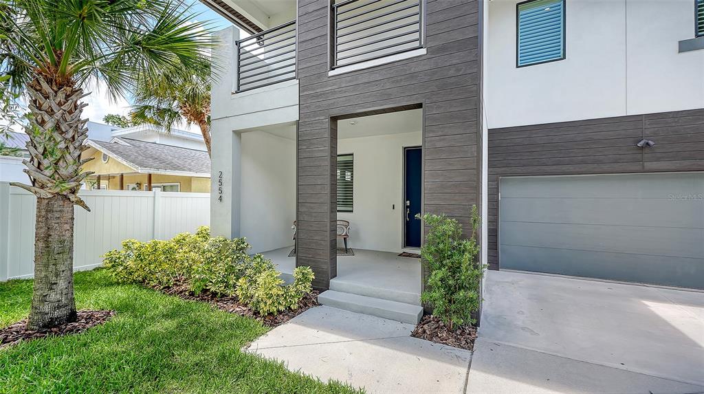 The exterior of a modern two-story house features a dark wood-paneled facade and garage — 2554 FLOYD STREET, SARASOTA, FL