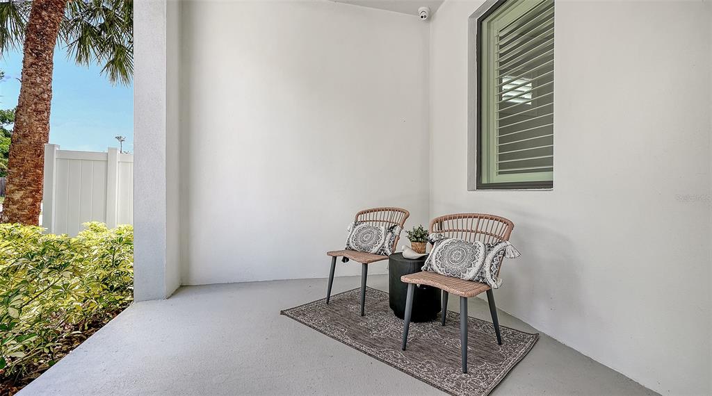 A covered patio features two wicker chairs, a small side table, and a patterned rug — 2554 FLOYD STREET, SARASOTA, FL