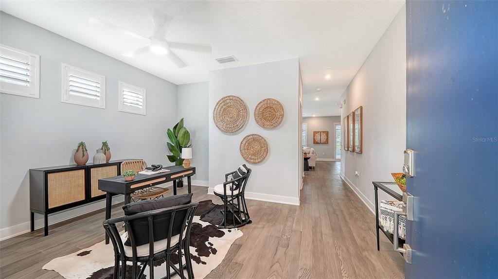 A home office features a desk, chairs, a cowhide rug, and wall-mounted woven decor — 2554 FLOYD STREET, SARASOTA, FL
