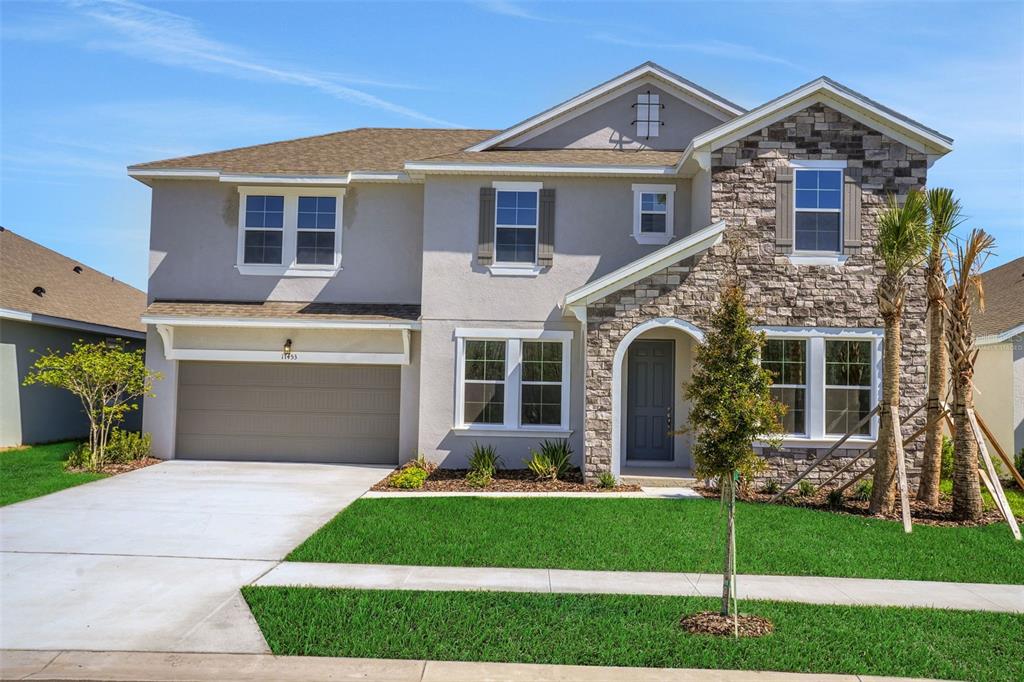 A two-story suburban house with a stone facade, gray stucco, and a two-car garage — 17453 VALLEYWOOD PARKWAY, LAND O LAKES, FL