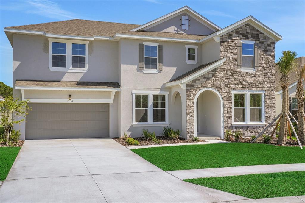 A two-story suburban house with a stone facade, beige stucco, and a two-car garage — 17453 VALLEYWOOD PARKWAY, LAND O LAKES, FL
