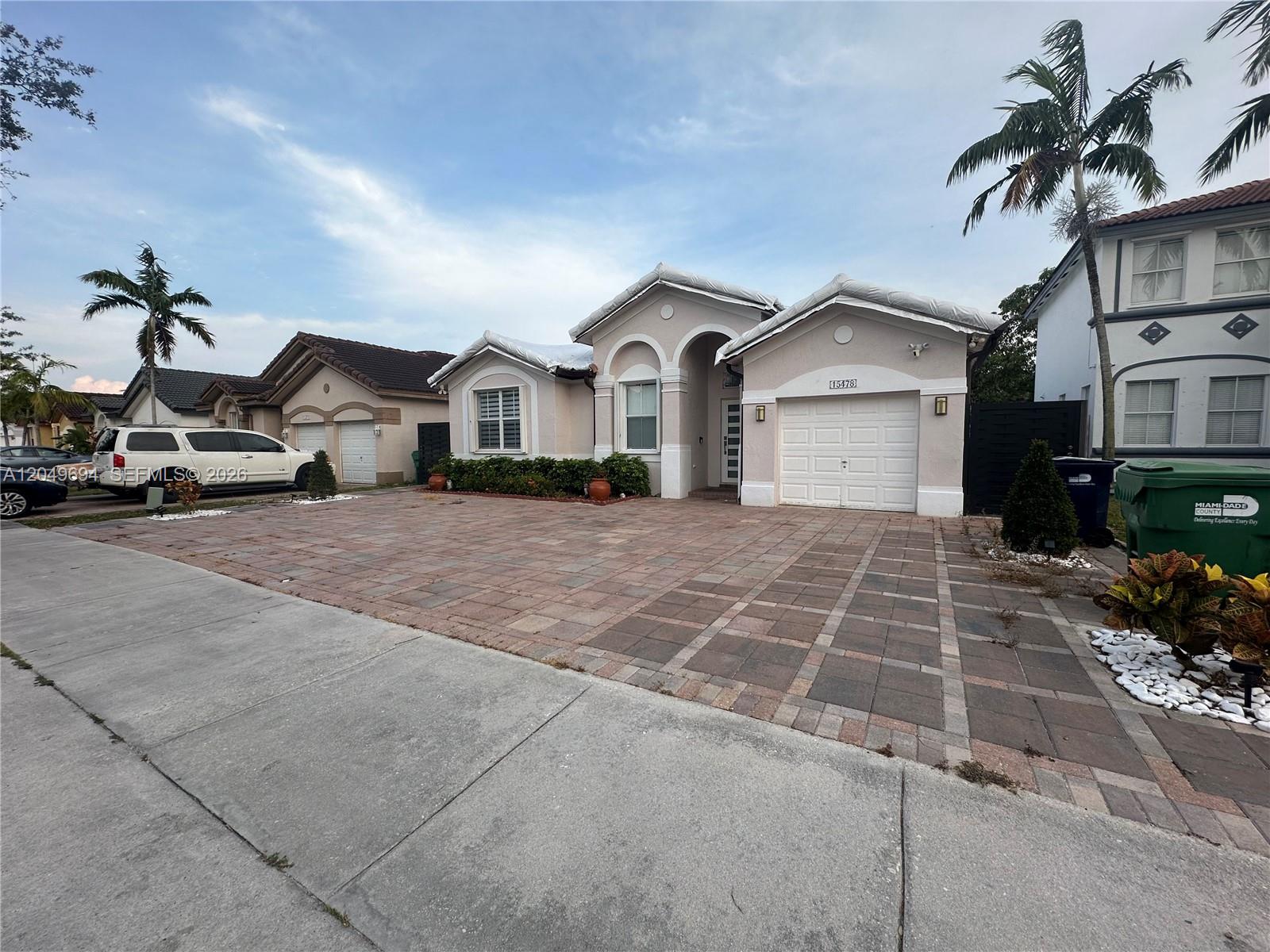 A single-story suburban house with a paved driveway, a garage, and palm trees — 15478 SW 23rd Ln # 15478, Miami FL 33185, MIAMI, FL