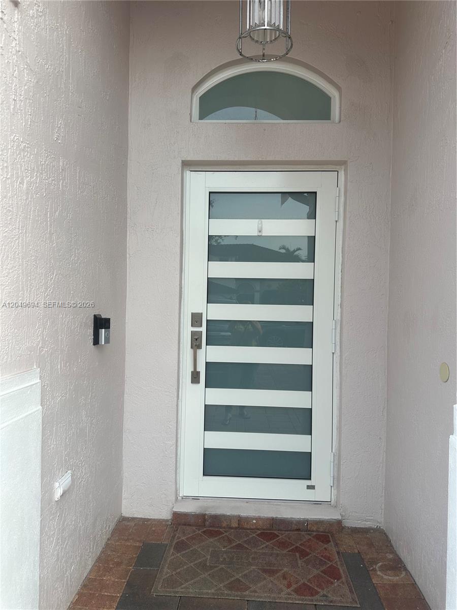 A modern white front door with horizontal glass panels is set in a stucco entryway — 15478 SW 23rd Ln # 15478, Miami FL 33185, MIAMI, FL