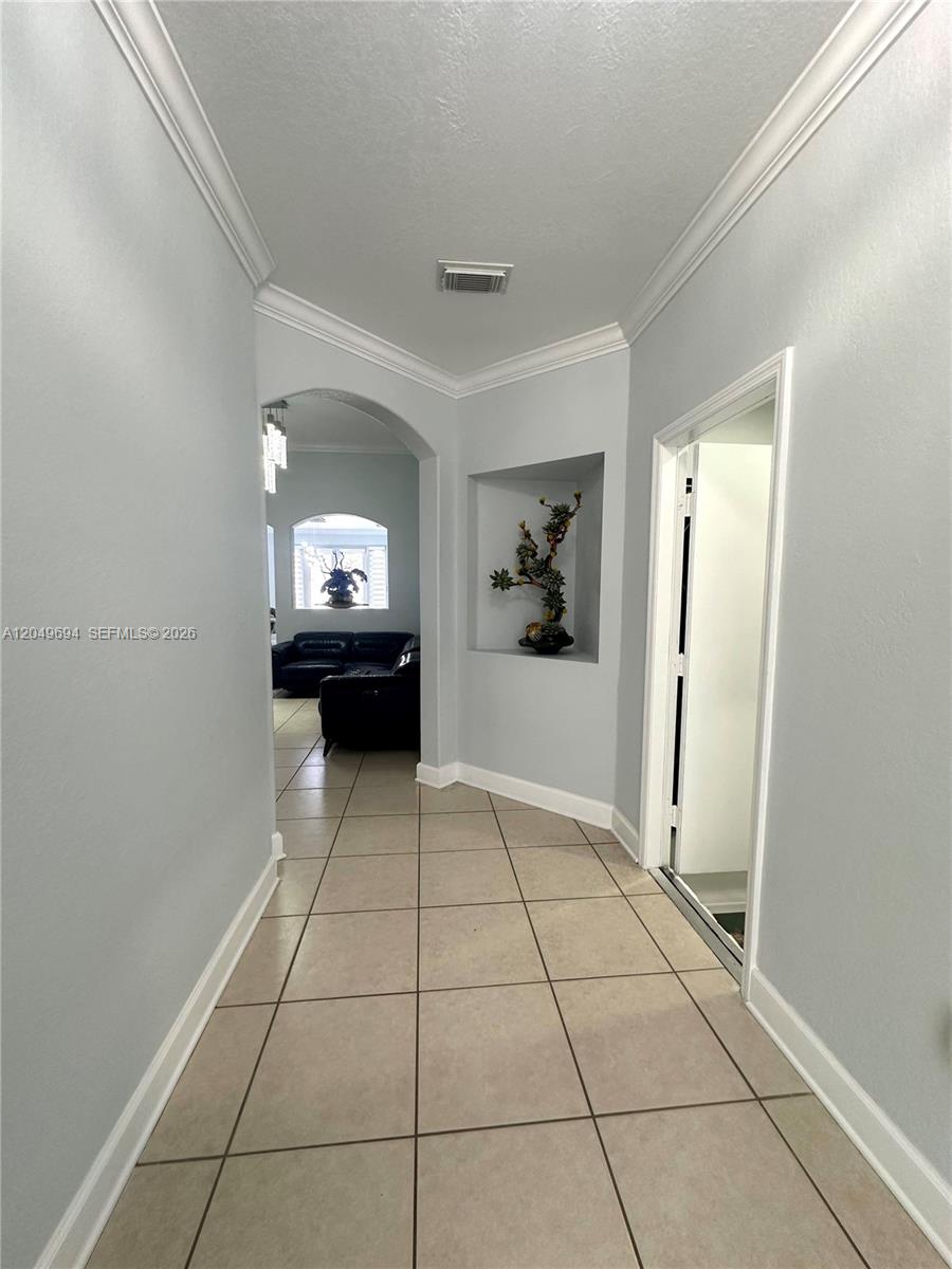 A tiled hallway leads through an arched doorway into a living room with a niche — 15478 SW 23rd Ln # 15478, Miami FL 33185, MIAMI, FL