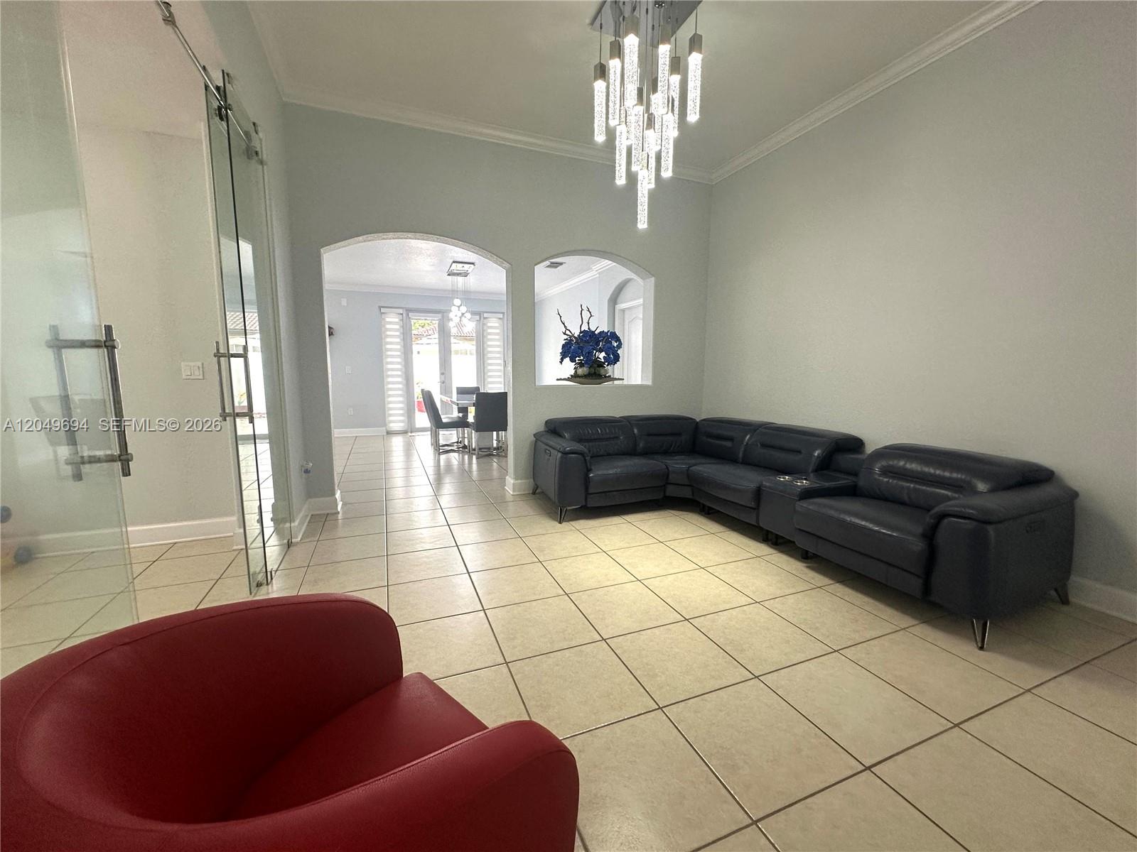 A living room features a dark leather sectional, a red chair, and a modern chandelier — 15478 SW 23rd Ln # 15478, Miami FL 33185, MIAMI, FL