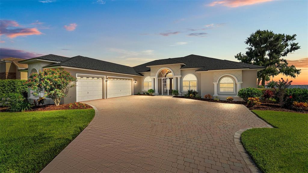 A single-story house with a paved driveway, a three-car garage, and a arched entryway — 7303 BIRDS NEST COURT, YALAHA, FL