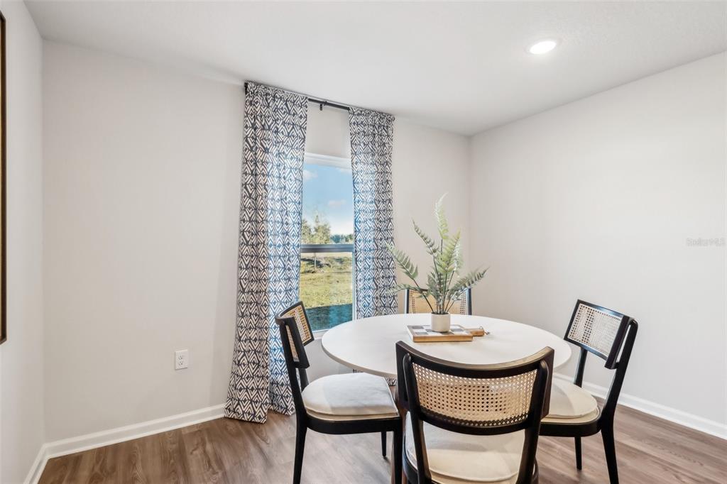 A dining area features a round white table, four chairs, and abstract wall art — 622 MONTCLAIR AVENUE S, LEHIGH ACRES, FL