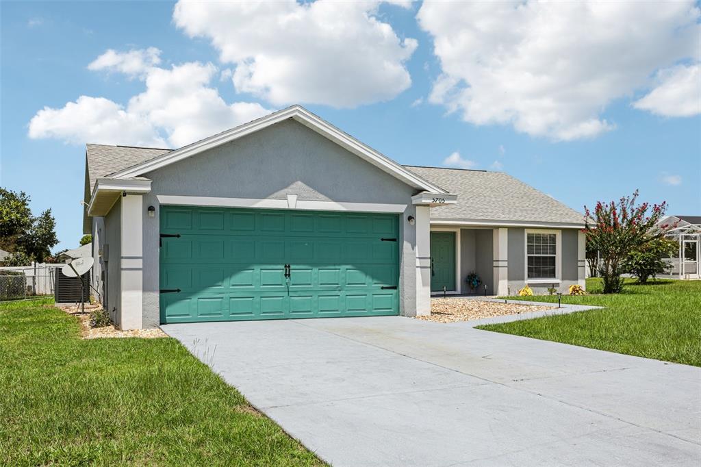 A single-story house with a teal garage door, gray siding, and a concrete driveway — 5705 SW 89TH PLACE, OCALA, FL