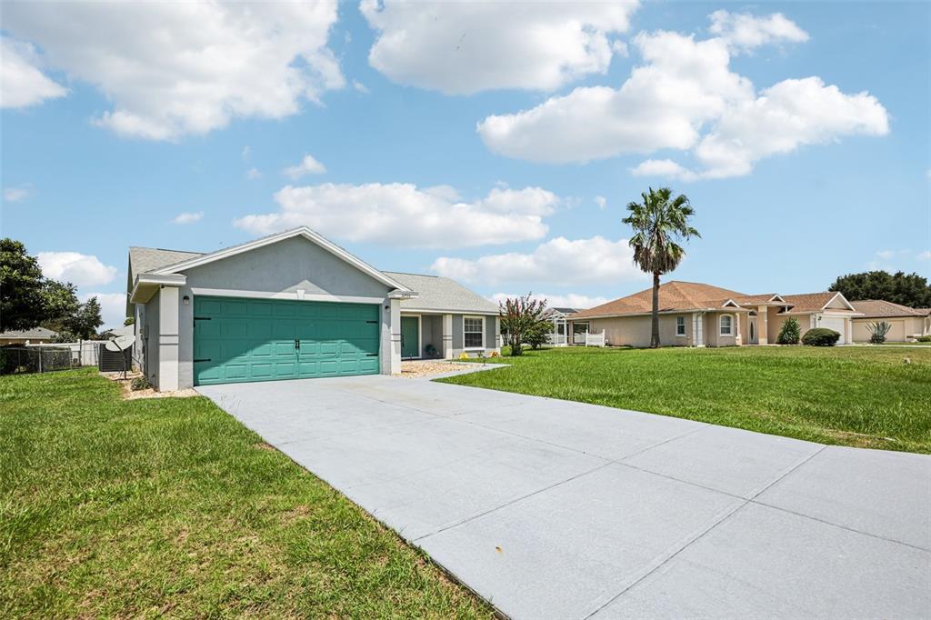 A single-story house with a teal garage door and a concrete driveway under a blue sky — 5705 SW 89TH PLACE, OCALA, FL