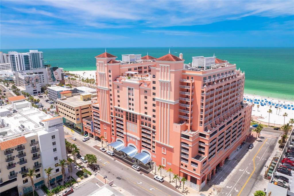 An aerial view of a large, pink multi-story hotel building located near a sandy beach — 301 S GULFVIEW BOULEVARD UNIT 604, CLEARWATER BEACH, FL