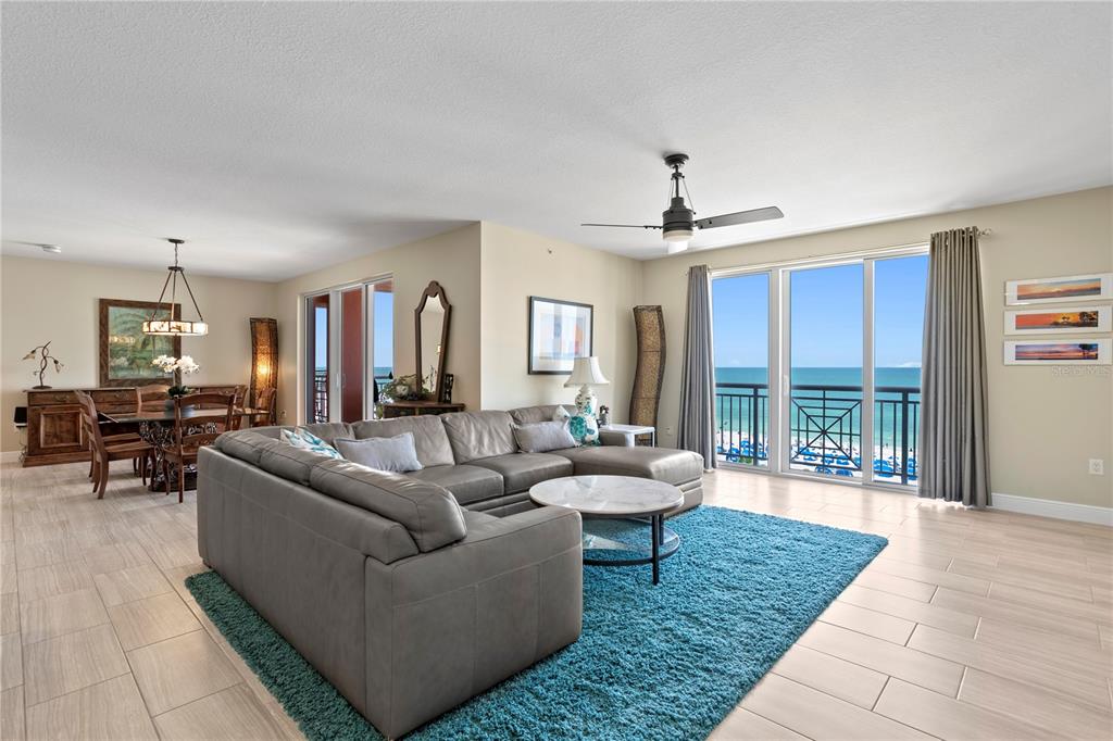 A living room with a gray sectional, blue rug, and sliding doors overlooking the ocean — 301 S GULFVIEW BOULEVARD UNIT 604, CLEARWATER BEACH, FL