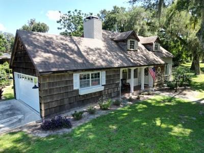 A two-story house with wood shingle siding, a front-facing garage, and a brick chimney — 35833 LAKESHORE DRIVE, DADE CITY, FL