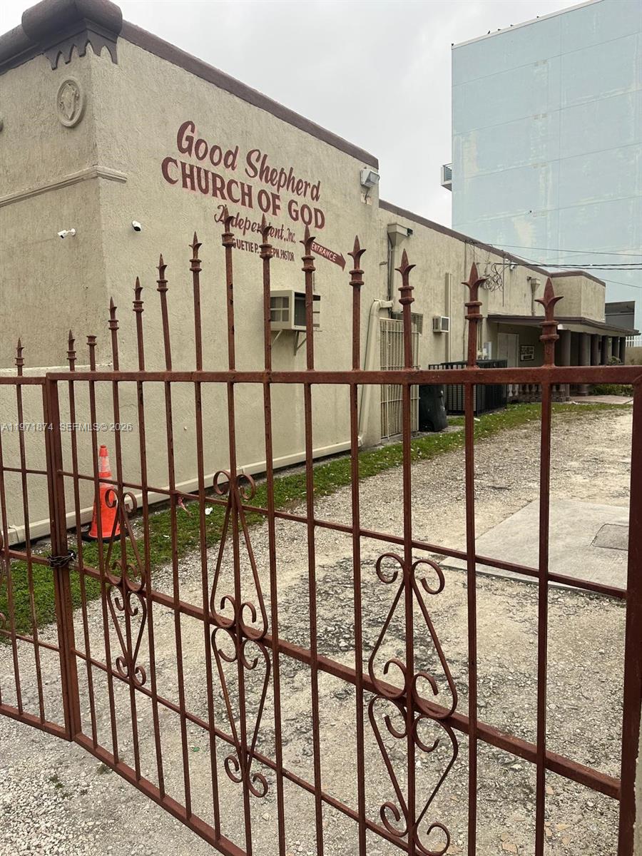 A metal gate stands in front of a beige building labeled Good Shepherd Church of God — 5301 NW 17th Ave, Miami FL 33142, MIAMI, FL