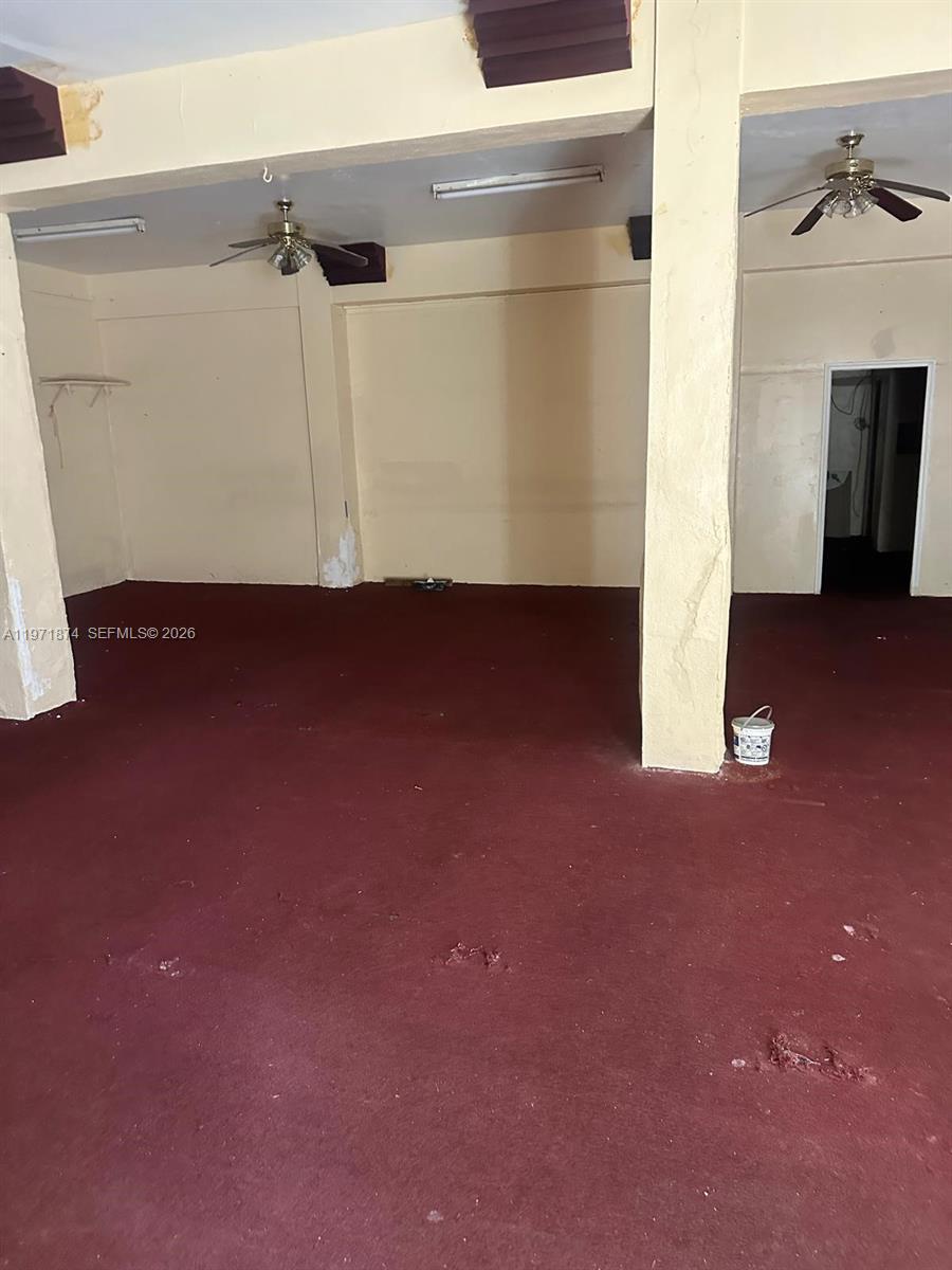 An empty commercial space features red carpeting, ceiling fans, and a doorway in the back — 5301 NW 17th Ave, Miami FL 33142, MIAMI, FL