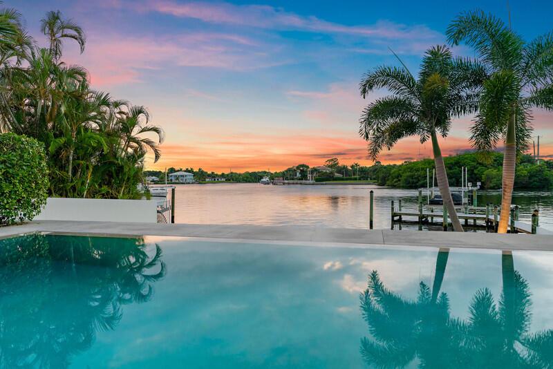 A swimming pool overlooks a calm waterway with a wooden dock and palm trees at sunset — 5706 Holly Lane, Jupiter FL 33458, JUPITER, FL