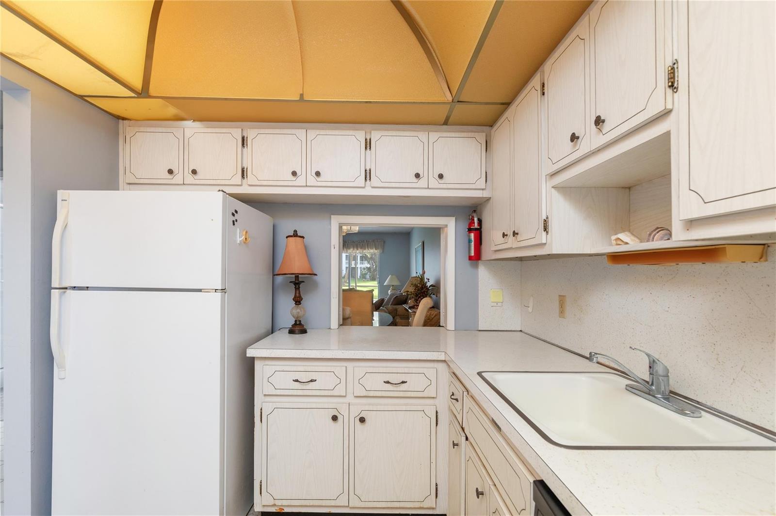 A kitchen features white cabinets, a white refrigerator, a sink, and a pass-through window — 2731 NE 14th St Causeway # 121, Pompano Beach FL 33062, POMPANO BEACH, FL