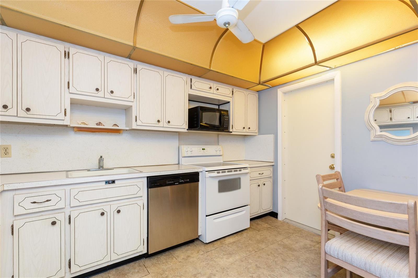 A kitchen features white cabinets, a stainless steel dishwasher, a white stove, and gold soffits — 2731 NE 14th St Causeway # 121, Pompano Beach FL 33062, POMPANO BEACH, FL