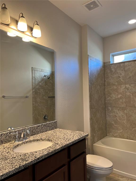 A bathroom features a granite vanity, a mirror, a toilet, and a tiled shower-tub combination — 17392 BAL HARBOUR DRIVE, WINTER GARDEN, FL