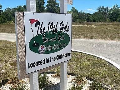 A sign for The 19th Hole Bar and Grill stands outdoors near a paved road — DAYTONA DRIVE, INDIAN LAKE ESTATES, FL