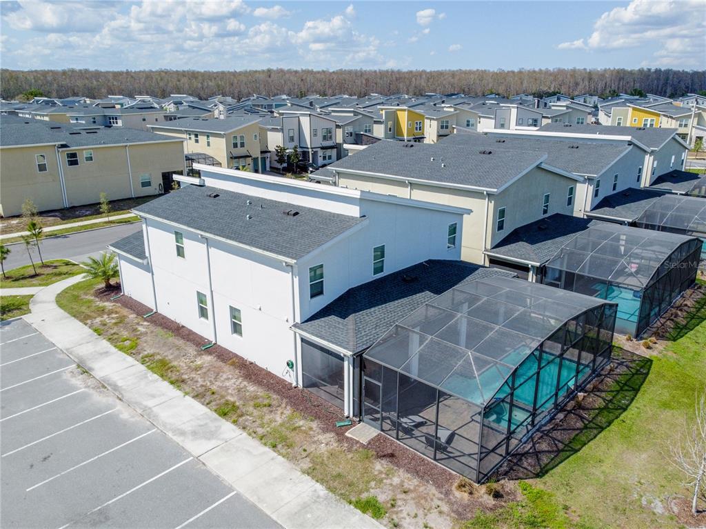 An aerial view shows a two-story house with a screened-in pool and adjacent parking lot — 2901 PROTAGONIST STREET, KISSIMMEE, FL