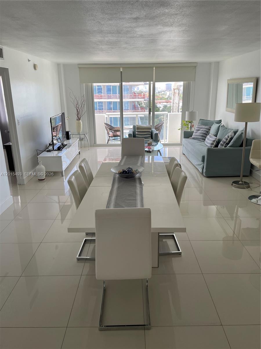 A balcony with a small table and two chairs overlooks the ocean and construction site — 9195 Collins Ave # 1012, Surfside FL 33154, SURFSIDE, FL