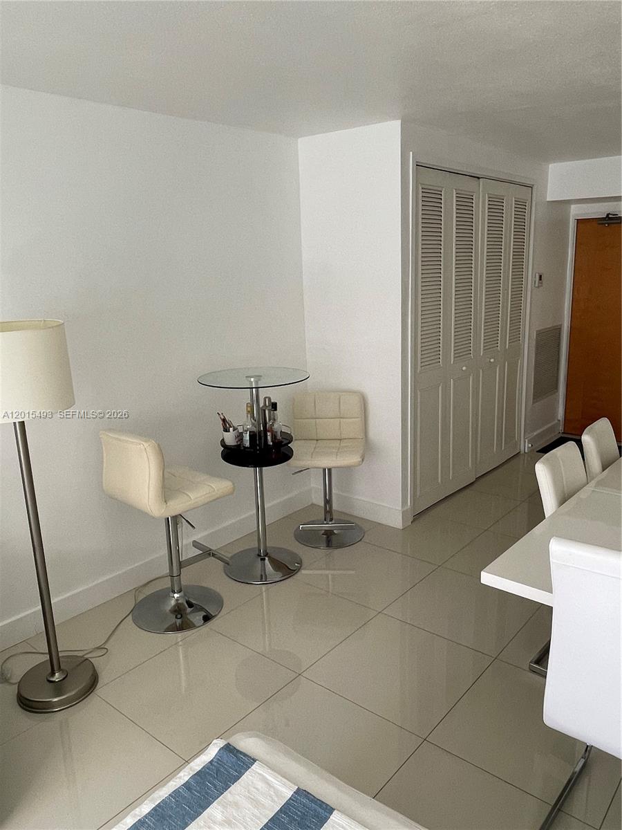 A kitchen features white cabinets, a white refrigerator, a dishwasher, and a small glass table — 9195 Collins Ave # 1012, Surfside FL 33154, SURFSIDE, FL