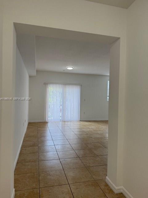 An interior view showing a tiled living area with vertical blinds covering a sliding door — 10870 NW 88th Ter # 223, Doral FL 33178, DORAL, FL