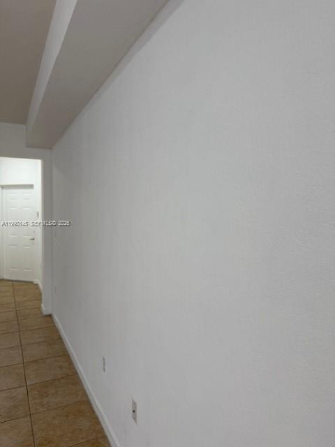 A long, white-walled hallway features tan tile flooring and a doorway at the end — 10870 NW 88th Ter # 223, Doral FL 33178, DORAL, FL