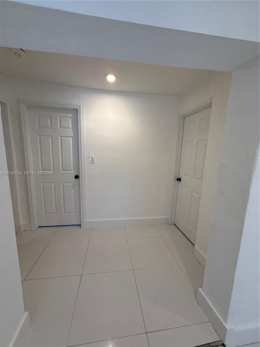 A small, white-walled hallway features two closed doors and light-colored square floor tiles — 6716 NW 6th Ave # 2, Miami FL 33150, MIAMI, FL