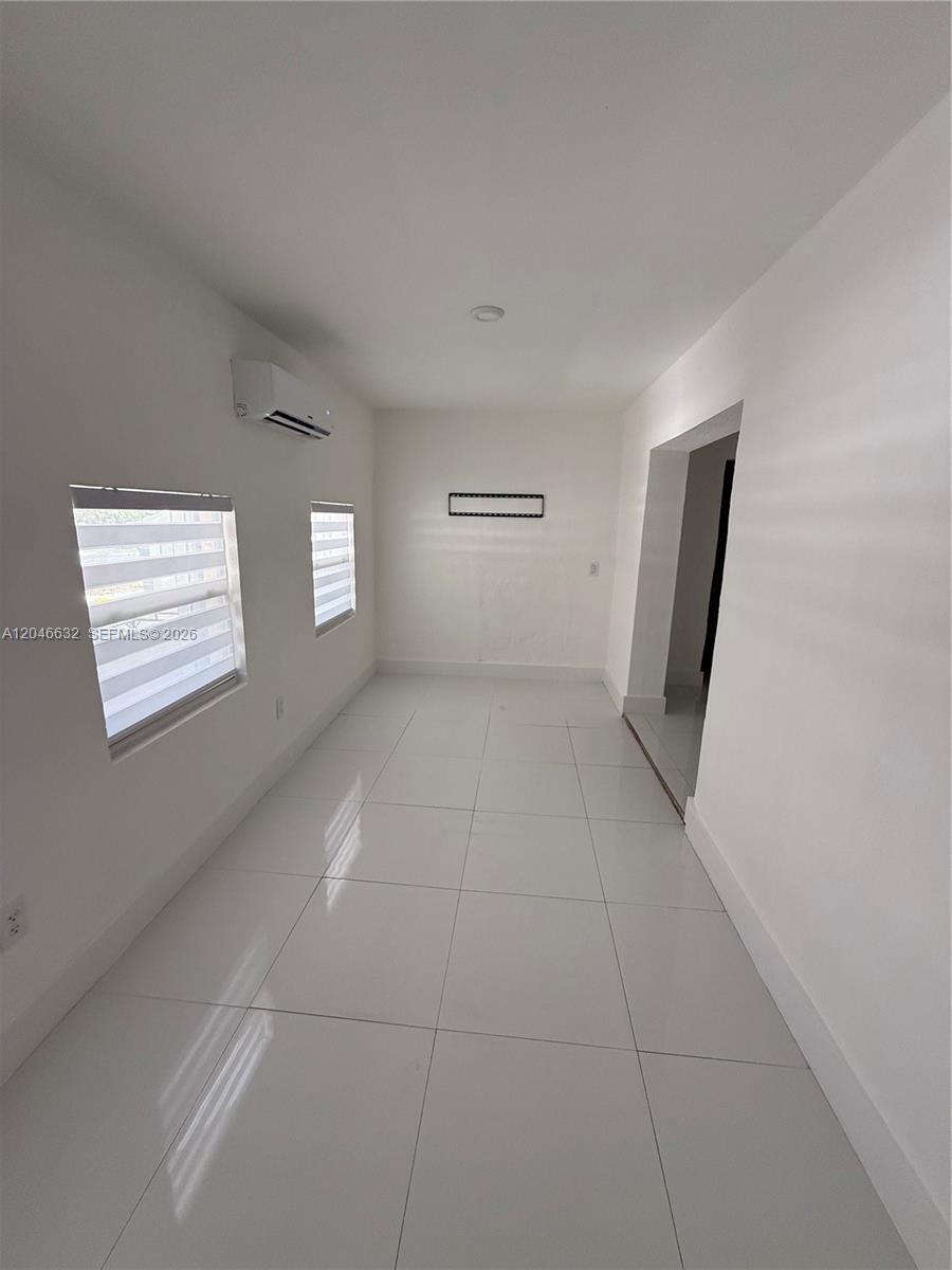 A narrow, empty room features white walls, large light-colored floor tiles, and a wall-mounted air conditioner — 6716 NW 6th Ave # 2, Miami FL 33150, MIAMI, FL