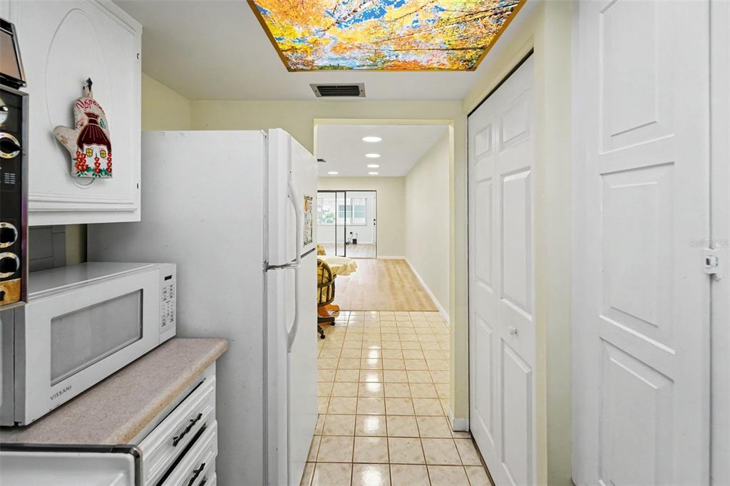 A kitchen with white cabinets and appliances leads into a dining area with tiled floors — 5870 38TH AVENUE N UNIT 43, ST PETERSBURG, FL