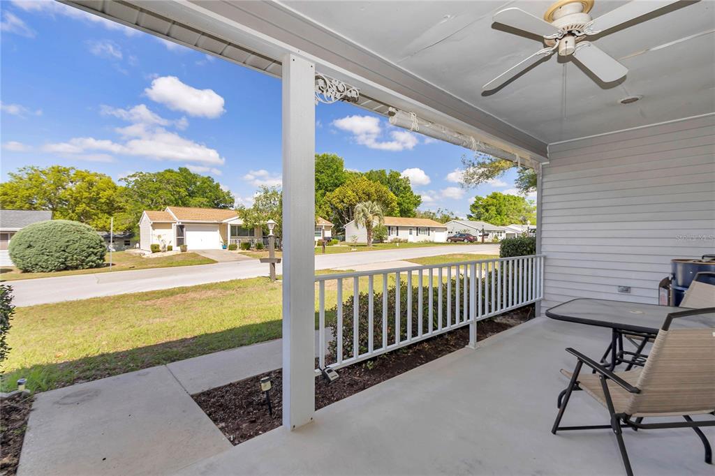 A covered porch features a ceiling fan, white railing, and a view of a suburban street — 10891 SW 89TH AVENUE, OCALA, FL