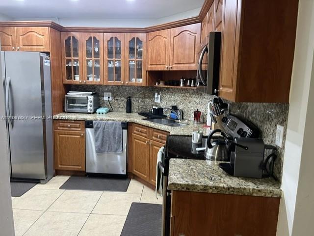 A kitchen features wood cabinets, granite countertops, stainless steel appliances, and tile flooring — 7410 SW 82nd St # K206, Miami FL 33143, MIAMI, FL