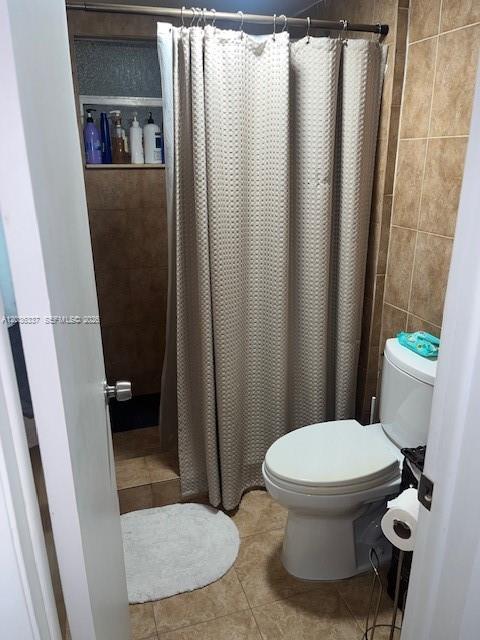 A bathroom features a toilet, a shower with a beige curtain, and tiled walls — 7410 SW 82nd St # K206, Miami FL 33143, MIAMI, FL