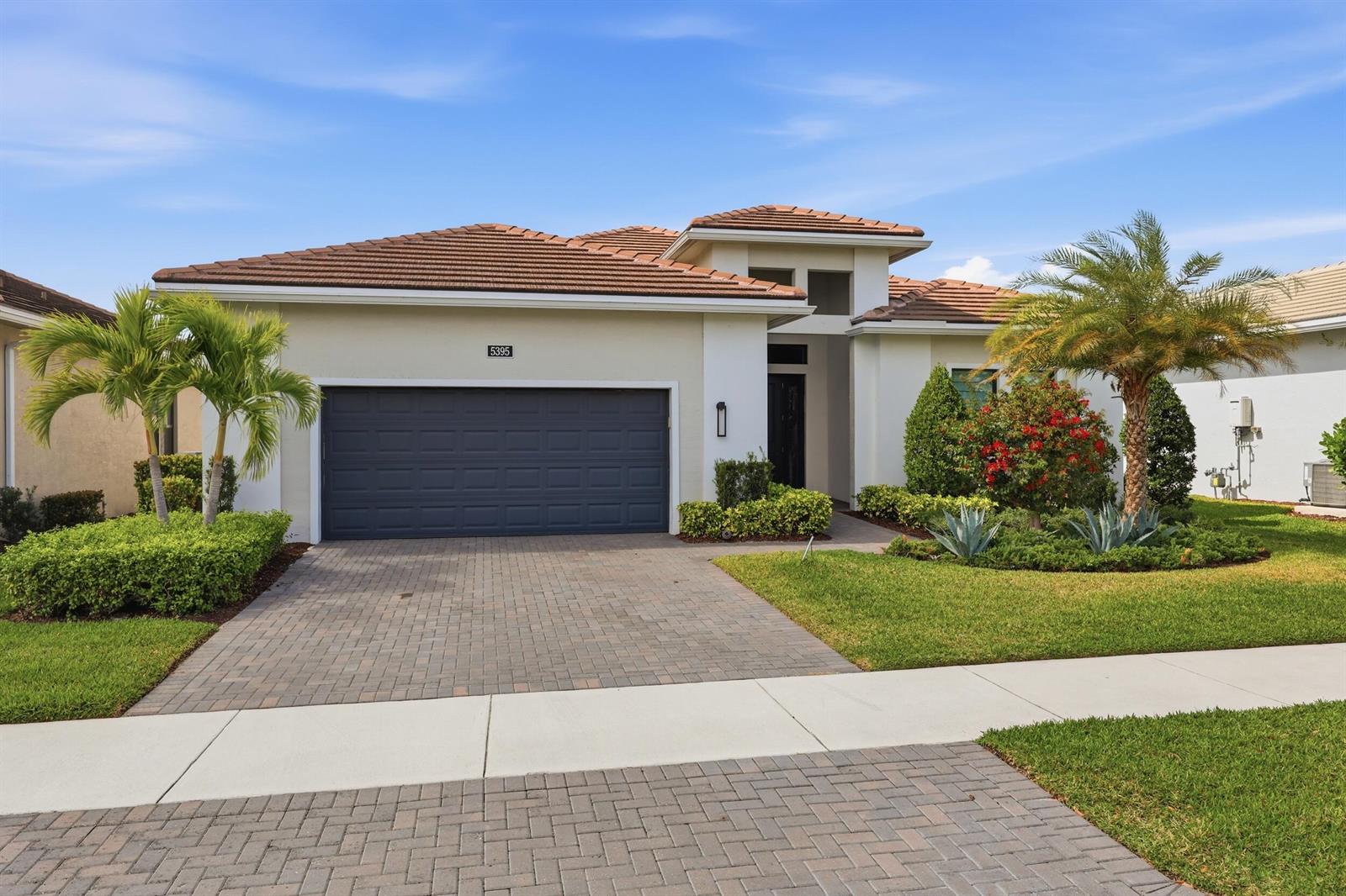 A single-story house with a tiled roof, a dark garage door, and a paved driveway — 5395 Saint Vincent Lane, FL 33470, FL
