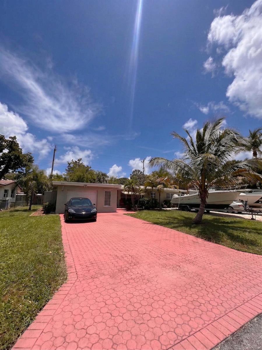 A single-story house with a boat parked in the driveway under a bright blue sky — 1230 NE 26th Terrace, Pompano Beach FL 33062, POMPANO BEACH, FL