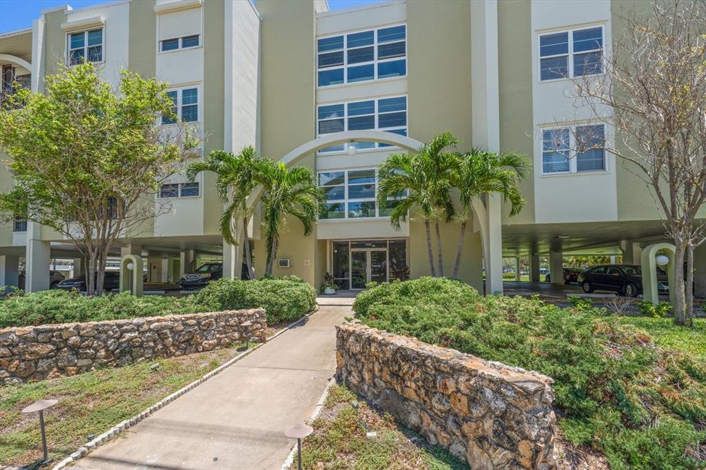 A concrete walkway leads to the entrance of a multi-story apartment building with covered parking — 4681 1ST STREET NE UNIT 308, ST PETERSBURG, FL