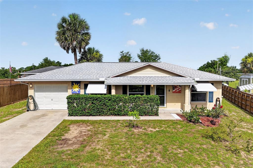 A single-story house with a white garage, a hedge-lined front porch, and a palm tree — 512 HIGHLAND DRIVE, EUSTIS, FL