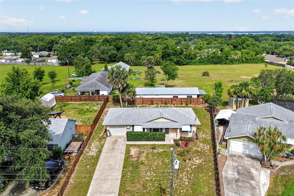 An aerial view shows a single-story house with a concrete driveway and a fenced yard — 512 HIGHLAND DRIVE, EUSTIS, FL