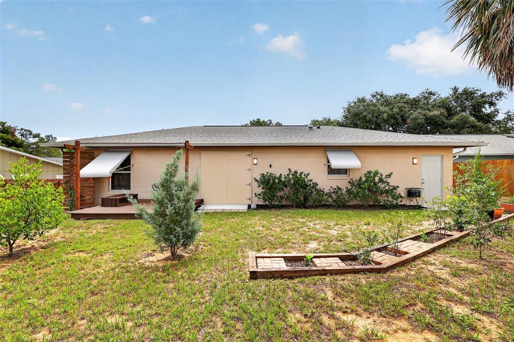 The exterior of a single-story house features a wooden deck, landscaping, and a grassy yard — 512 HIGHLAND DRIVE, EUSTIS, FL