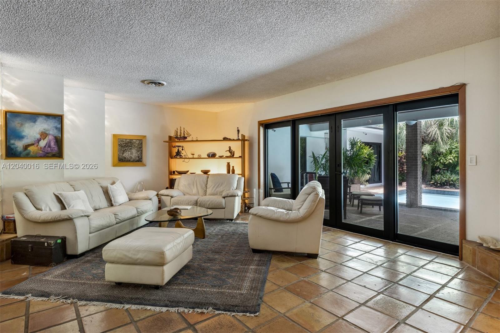 A living room with white leather furniture, a patterned rug, and sliding glass doors — 11100 SW 67th Ave, Pinecrest FL 33156, PINECREST, FL